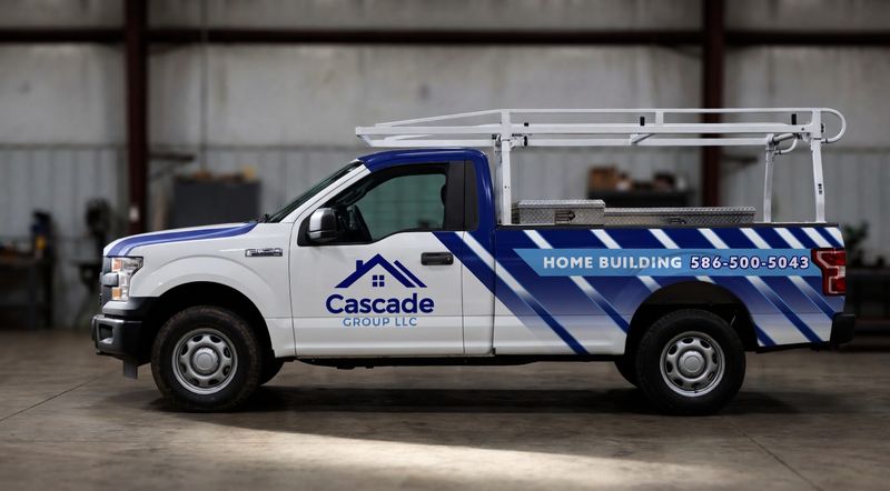 Concept mockup: white Ford F-150 pickup with a ladder rack, side view, with blue diagonal-stripe partial wrap on the bed, a hood stripe, a house-roof "Cascade Group LLC" logo on the door, and a "Home Building" banner.
