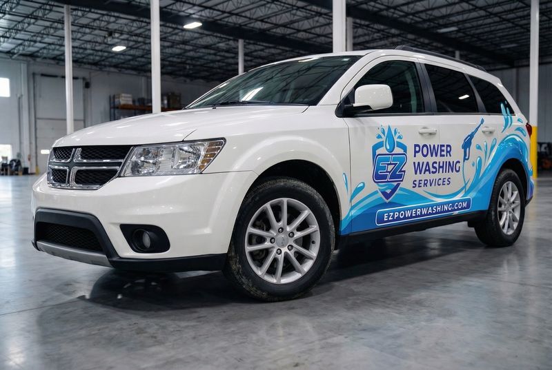 Concept mockup: white Dodge Journey SUV, front three-quarter view, showing the blue splash partial wrap and "EZ Power Washing Services" logo on the rear doors.
